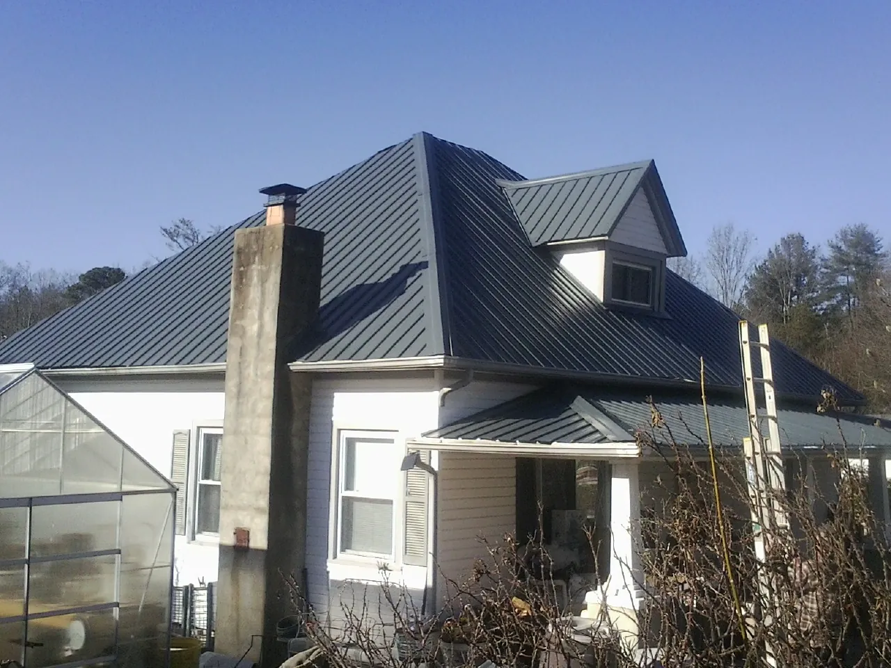 Dark blue standing seam metal roof on a white farmhouse with dormer — Slate & Tile Roof Repair by Roofing Brothers in Statham