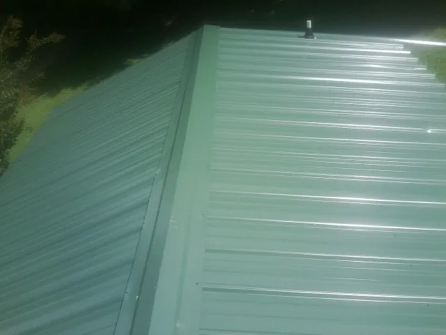 New green metal panels meeting at the ridge of a roof — Flat Roof Repair work by our crew in Statham