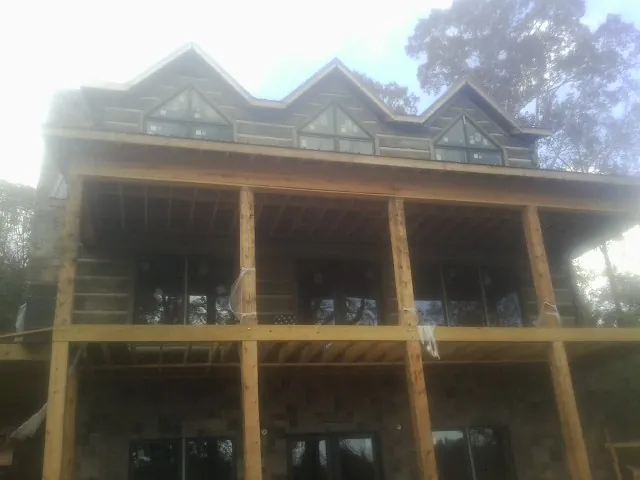 Dormers and porch framing on a large log home under construction — Roof Coating work by our crew in Statham