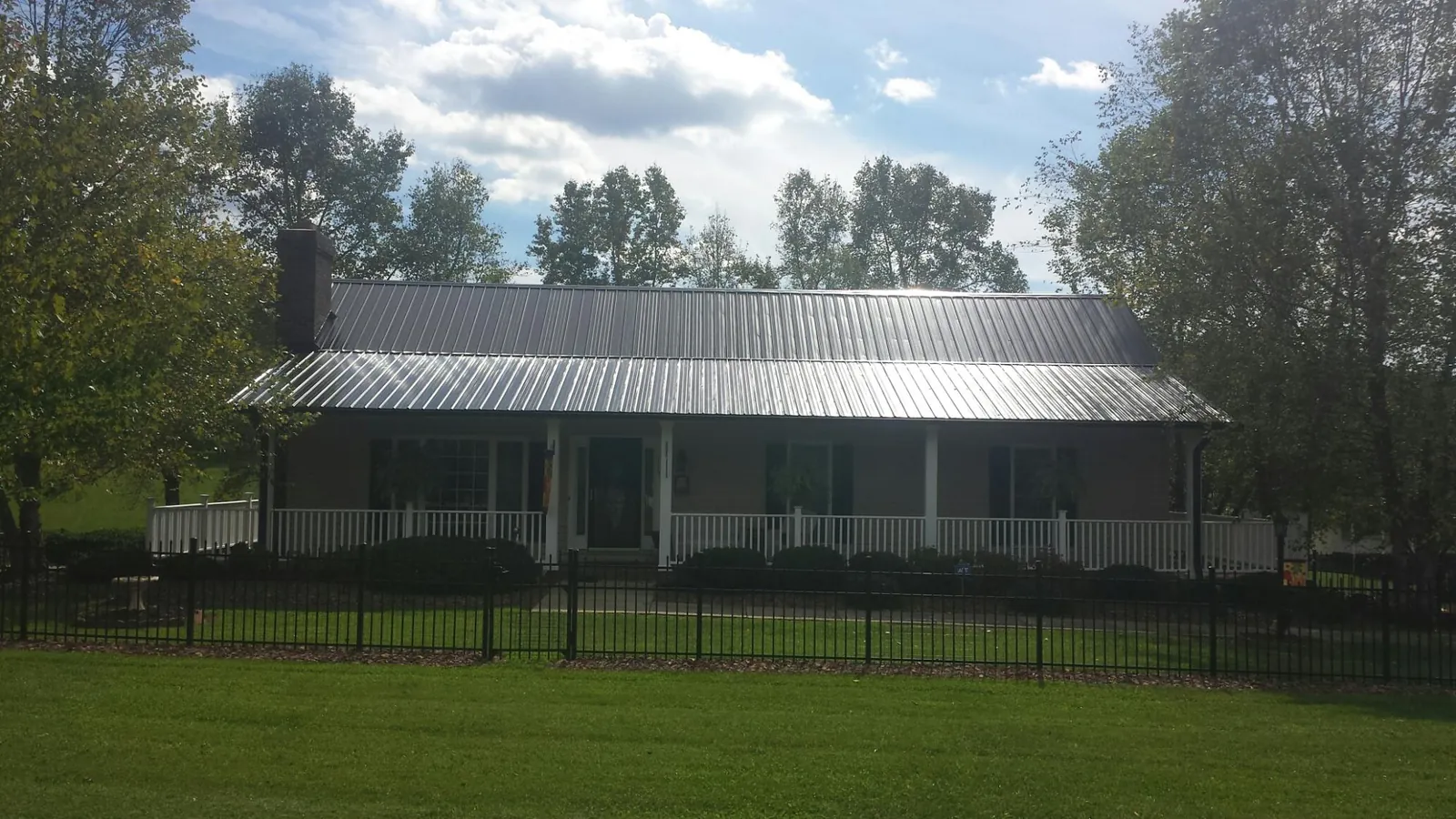 Gray metal roof on a brick ranch with a full width front porch — Gutter Guard Installation work by our crew in Statham