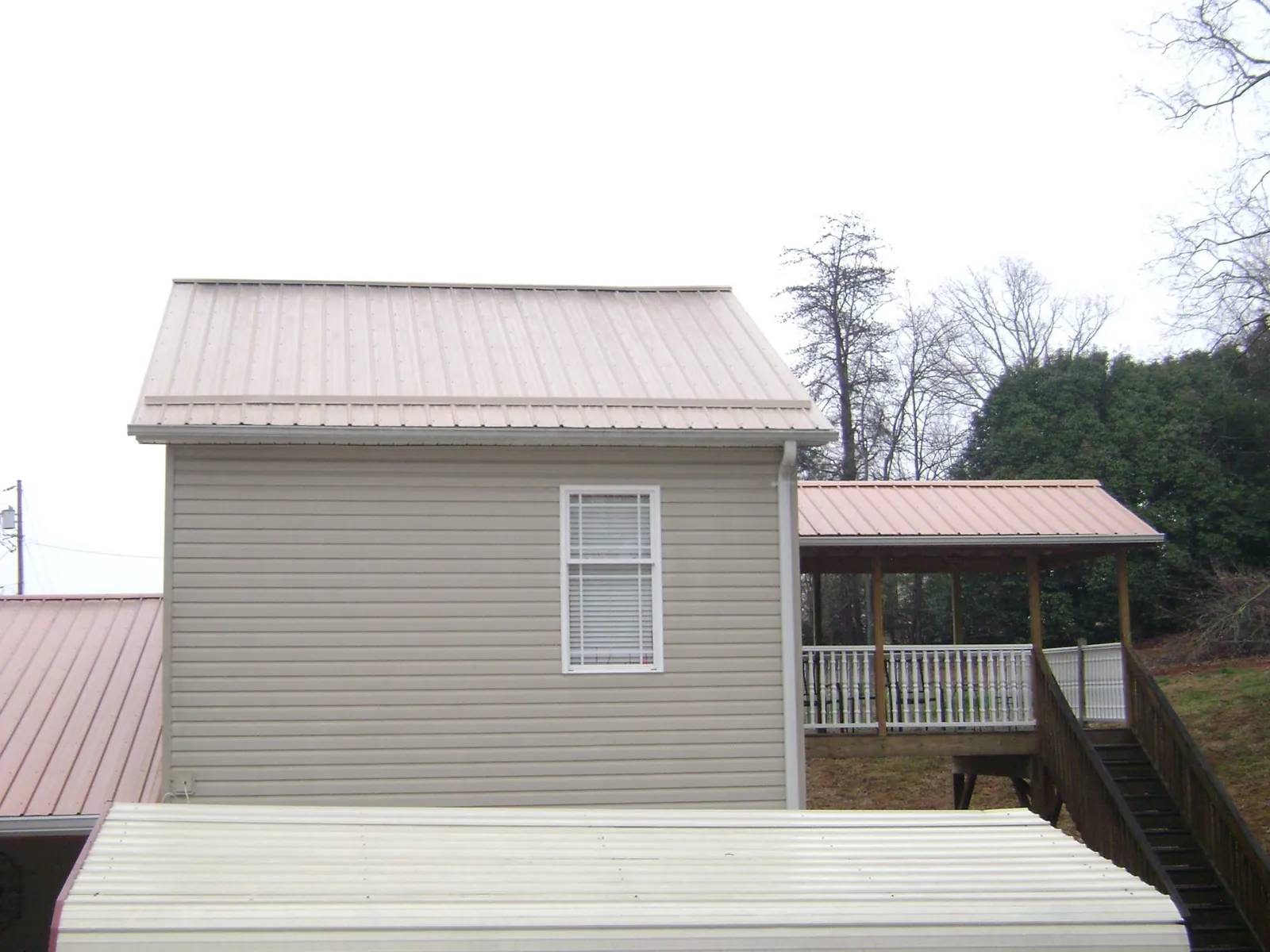 Tan metal roofs on a two story addition and attached porch, from a Roof Replacement job in Statham