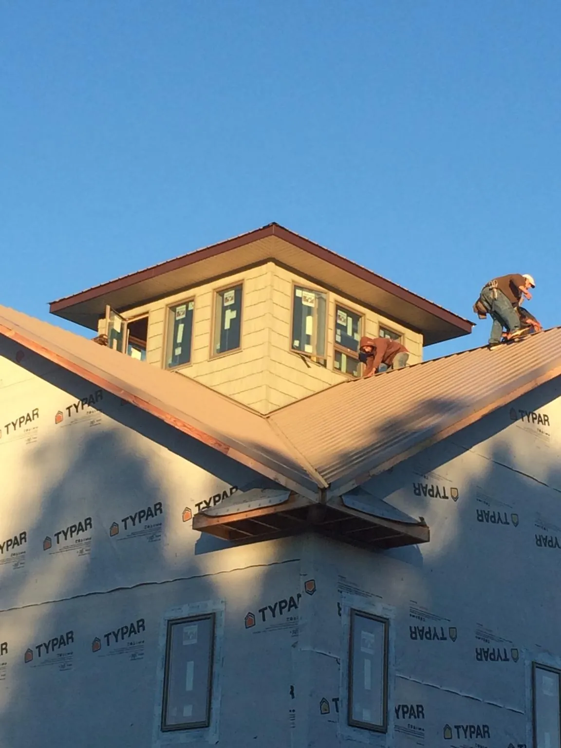 Roofers working around a rooftop cupola on a new metal roof at sunset — Roof Waterproofing in Statham by Roofing Brothers